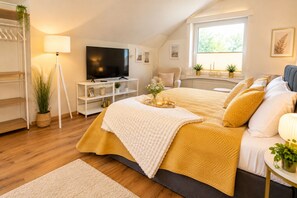 Quarto com cama, televisão, janela e planta.