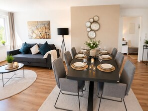 A modern living room with a dining area, a sofa, a coffee table, and a floor lamp. - Arrive & Feel at Home • Fireplace • calm • Parking Lot (Paderborn)