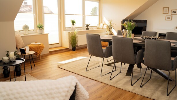 Un salon moderne comprenant un coin repas, de grandes fenêtres, un téléviseur à écran plat et une cheminée chaleureuse.
