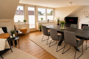 A modern living room with a dining area, large windows, a fireplace, and a flat-screen TV. - Arrive & Feel at Home • Fireplace • calm • Parking Lot (Paderborn)