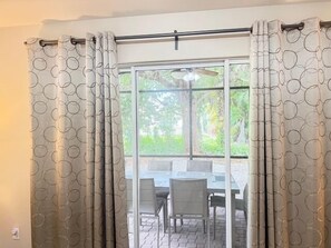 A room with a sliding glass door, a ceiling fan, and a table with chairs. - Family-Friendly Coastal Chic Home | Lanai Living | Perfect Snowbird Getaway (Naples)