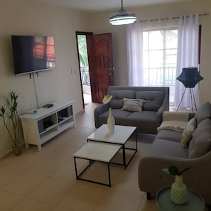 A living room with a sofa, coffee table, TV, and a potted plant. - 2BR Condo With Pool, Walk to Beach, Bávaro (Punta Cana)