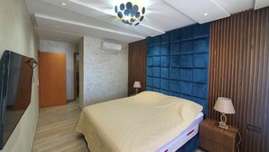 Ein Hotelzimmer mit Bett, Nachttischlampen, einer Deckenleuchte und einem Holznachttisch.
