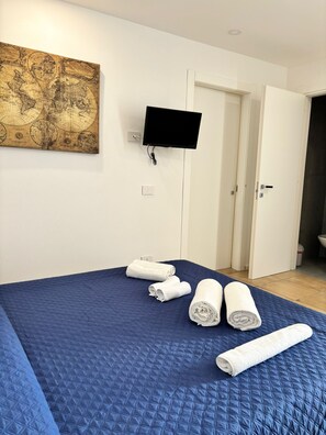 Ein Hotelzimmer mit einem großen Bett, einem flachbildfernseher an der Wand und einem Wandbild mit einer Landkarte.