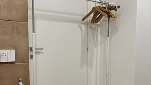 A room with a white door, a white metal rack with a wooden hanger, and a white metal cart with wheels. - At Casuzza di Giù Giù: Experience your stay in the historic center of Agrigento! (Agrigento)