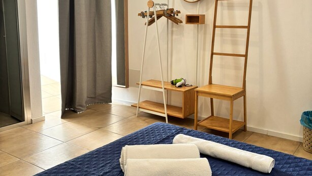 A hotel room with a bed, towels, a ladder, a mirror, and an air conditioning unit. - At Casuzza di Giù Giù: Experience your stay in the historic center of Agrigento! (Agrigento)