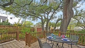 A wooden deck with a table and chairs, surrounded by trees and a fence. - Park Free  Walk to SoCo  Ride to DT/UT/COTA (Austin)