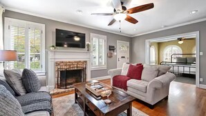 A living room with a fireplace, a ceiling fan, and a television. - Park Free  Walk to SoCo  Ride to DT/UT/COTA (Austin)