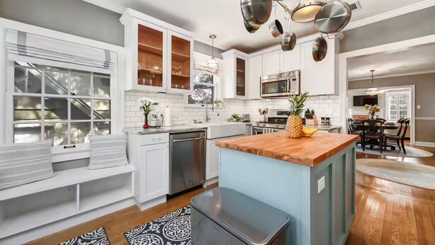 A modern kitchen with white cabinetry, a wooden island, stainless steel appliances, and a dining area with a table and chairs. - Park Free  Walk to SoCo  Ride to DT/UT/COTA (Austin)