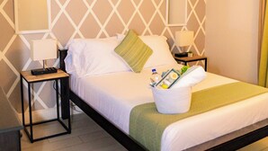 Ein ordentlich bezogenes Bett mit Kissen und Decke, zwei Nachttische mit Lampen, ein Wanddekor und ein Holzboden.