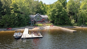 A lakeside cabin with a dock, surrounded by dense forest.