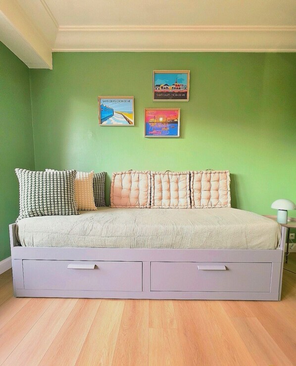 Quarto com cama, paredes verdes e duas quadros emolduradas.