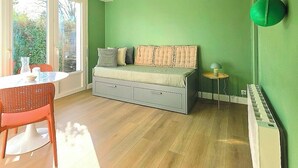 A room with a sofa, a dining table, and a lamp. - Studio St Gilles X Vie between beach, town and port. (Saint-Gilles-Croix-de-Vie)