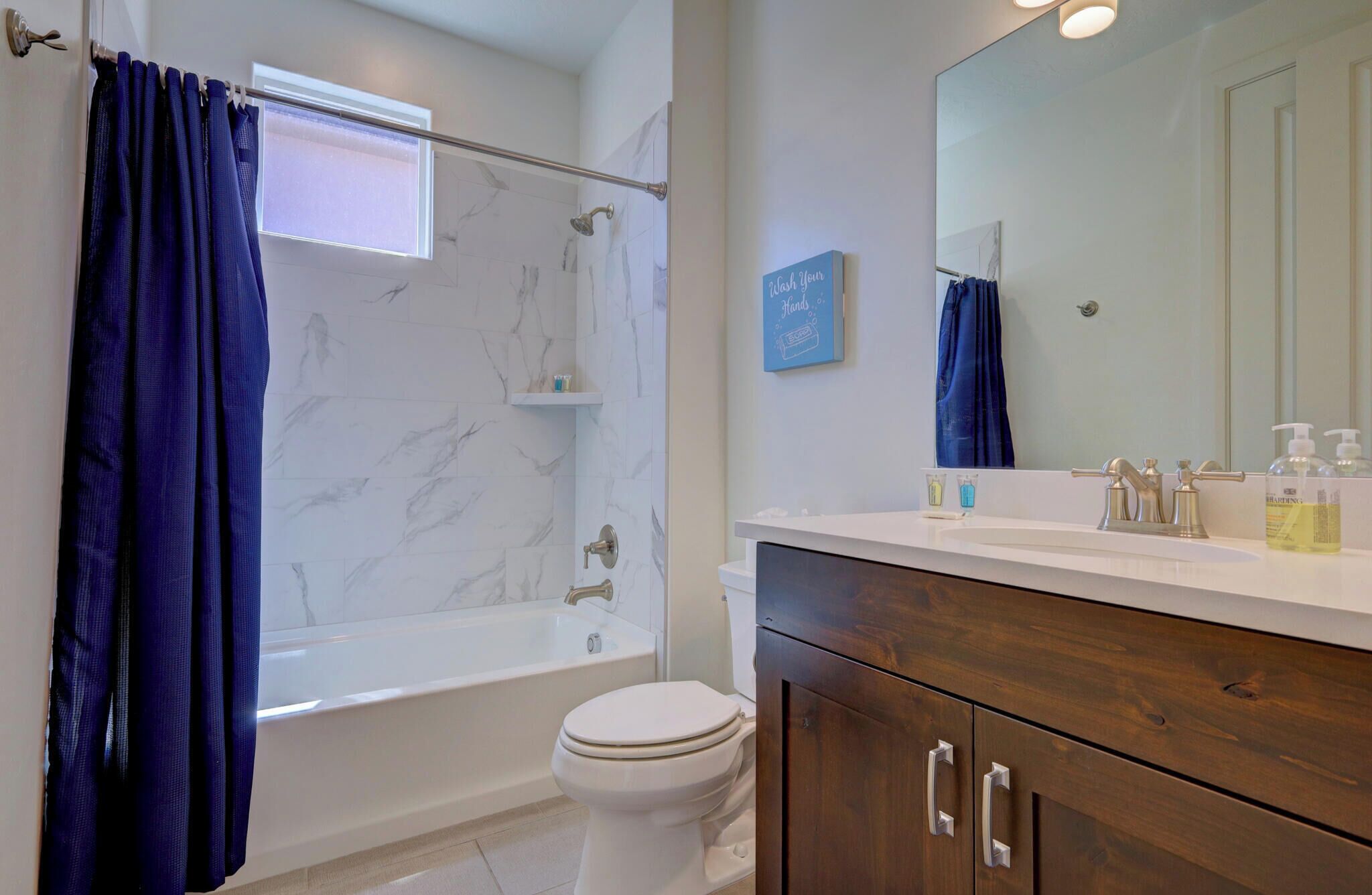 A bathroom with a bathtub, toilet, and vanity with a mirror.
