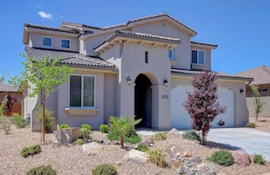A two-story house with a tiled roof, a central entrance with an archway, and a garage door.