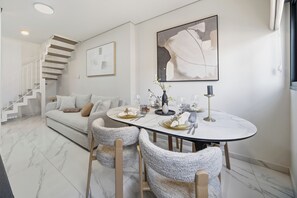 Ein moderner Essbereich mit einem runden Tisch, Stühlen und einer Treppe im Hintergrund.