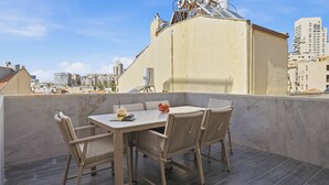 A rooftop terrace with a table and chairs, a tiled floor, and a cityscape view. - Spacious Family Duplex- The Shouk House (Jerusalem)