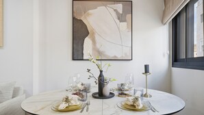 A dining table set with plates, glasses, and a vase with flowers. - Spacious Family Duplex- The Shouk House (Jerusalem)