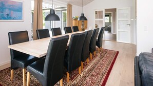 Ein zeitgemäßer Essbereich mit einem langen Tisch, schwarzen Stühlen und Pendelleuchten.