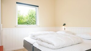Ein Schlafzimmer mit einem Bett, einem Fenster und einer Nachttischlampe.