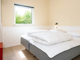 Un dormitorio con una cama, una ventana y una lámpara de noche.