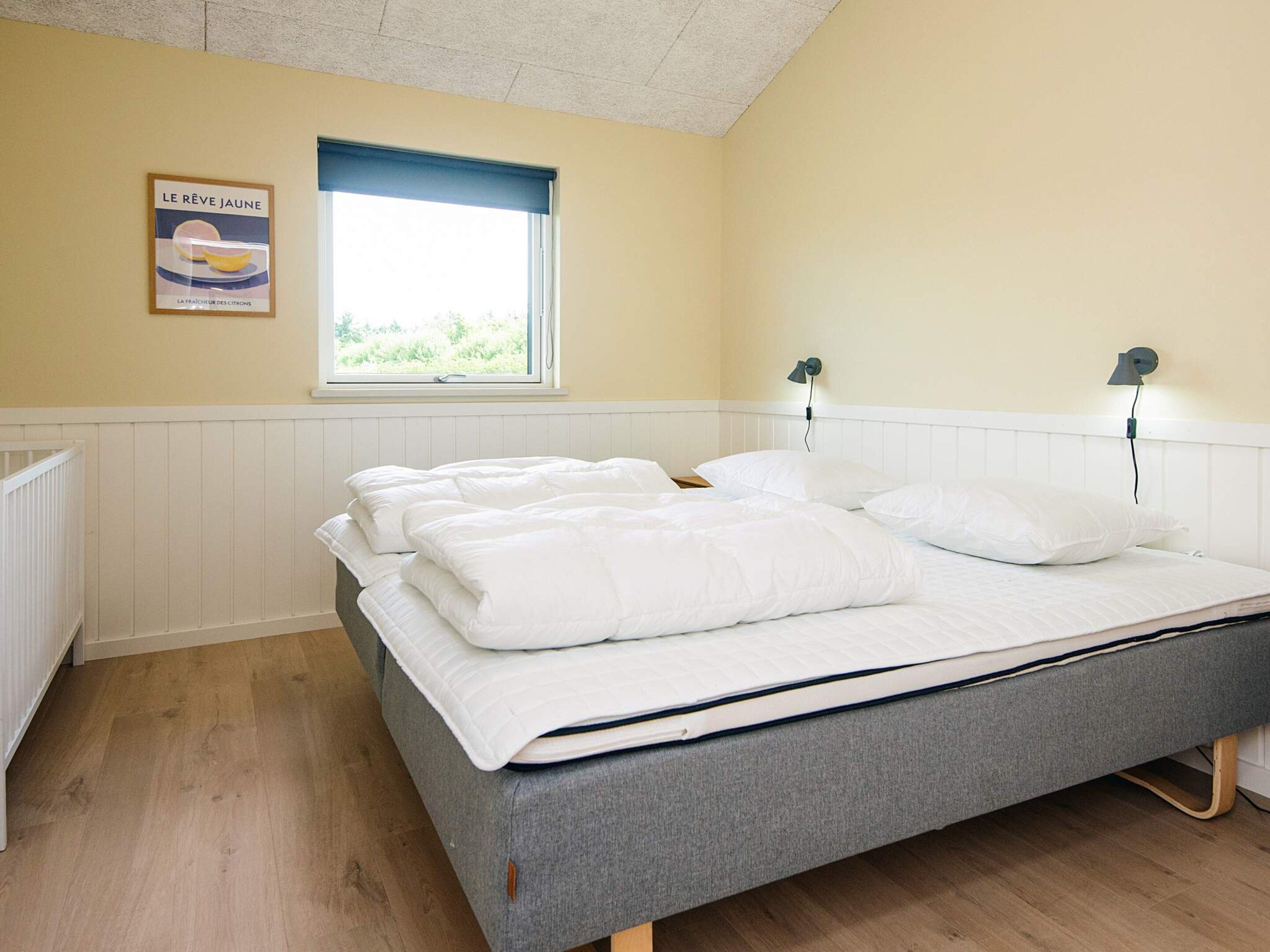 A bedroom with a bed, a window, a radiator, and a wall-mounted lamp.