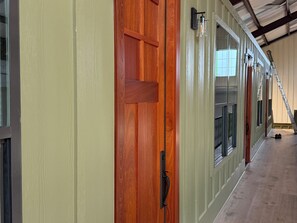 A hallway with a wooden door, metal-framed windows, and a ladder. - Luxury Giraffe experience in our luxurious 4 bedroom solar powered Giraffe House (Lometa)