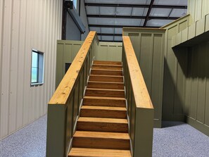A wooden staircase with a handrail, leading to a landing with a small window. - Luxury Giraffe experience in our luxurious 4 bedroom solar powered Giraffe House (Lometa)