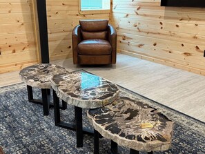 Ein Zimmer mit einem braunen Ledersessel, einem blauen Teppich mit Muster und drei runden Tischen mit schwarz-weißen, marmorähnlichen Platten.
