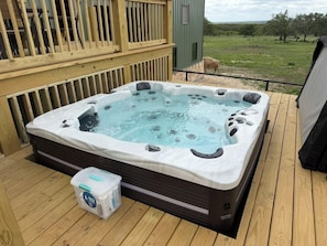 A hot tub on a wooden deck with a view of the countryside.