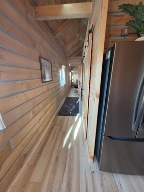 A wooden interior with a refrigerator, a rug, and a plant.