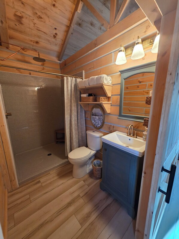 A wooden interior with a shower, toilet, and sink.