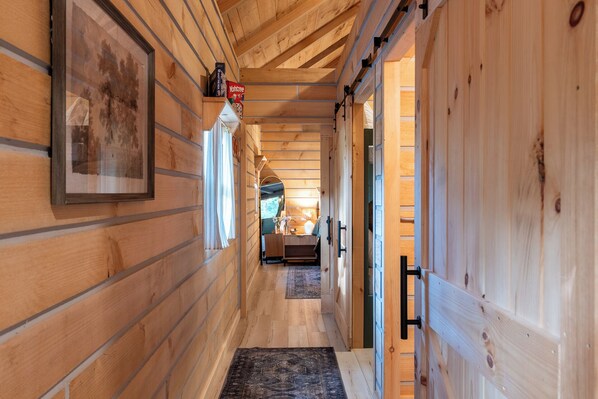 A wooden interior hallway with a door, a framed picture, and a rug.