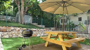A picnic table with a grill and umbrella in a landscaped outdoor area. - Near Beach 2BR Private Backyard, Grill & Laundry (Pelican key)