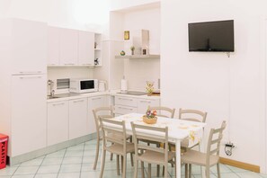 A compact kitchen with white cabinets, a microwave, a sink, and a dining table with chairs. - Nice apartment in central area, 10 minutes from the train station (Sant'Agnello)