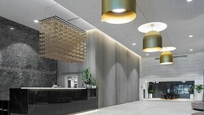 Et moderne receptionsområde med en marmor disk, lodrette lyspaneler og hængende lamper.