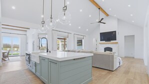A spacious kitchen with a large island, pendant lights, and a built-in fireplace. - Modern Luxury Retreat w/ Pool, Spa & Sunset Views (Wallkill)