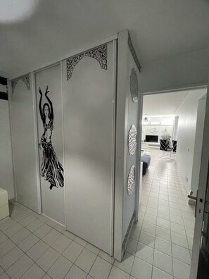 A room with a sliding door featuring a black and white decorative design, tiled flooring, and a glimpse of a living area with a sofa and a TV. - Oriental escape in the heart of Fort-de-France (Fort-de-France)