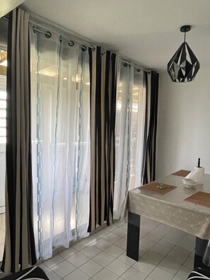 Una habitación con una mesa de comedor, cortinas y una lámpara colgante.