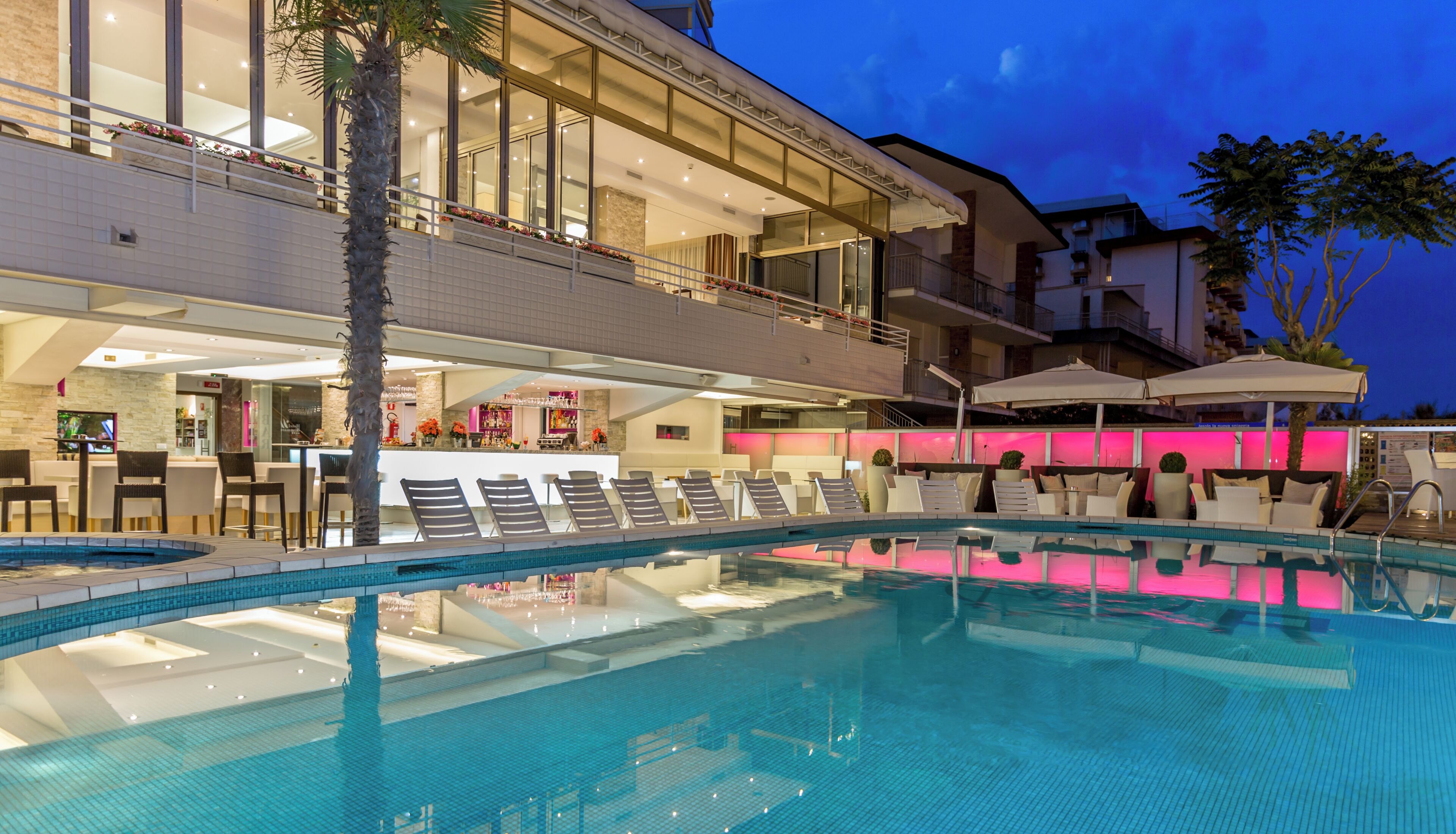 A swimming pool with lounge chairs, a bar area, and a restaurant.