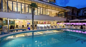 Un hôtel doté d’une piscine, de chaises longues et d’un bar.
