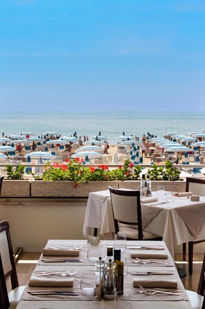 A beachside restaurant with tables set for dining, overlooking the sea. - Hotel Rivamare Jesolo (Jesolo)