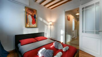 A hotel room with a bed, a painting, a lamp, and a door.