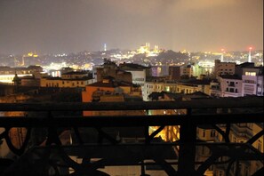 A nighttime cityscape with illuminated buildings and a distant hilltop structure. - Galata Tower at Your Fingertips Private (Istanbul)