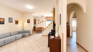 Una sala de estar con sofá, comedor y cocina visibles a través de un arco.