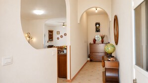 Un pasillo con un aparador de madera, un globo terráqueo y un reloj en la pared.