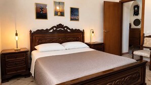 Un dormitorio con una cama de madera, dos mesitas de noche, una silla y una puerta.