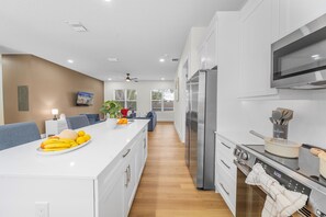 A modern kitchen with a central island, stainless steel appliances, and a dining area with a sofa. - Ultimate Tampa Stay | Dual Units • 6BR • Sleeps 17 (Tampa)