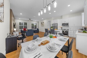 A modern kitchen with white cabinets, a microwave, and a refrigerator. - Ultimate Tampa Stay | Dual Units • 6BR • Sleeps 17 (Tampa)