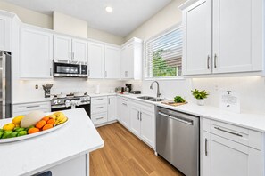 Una cocina moderna con armarios blancos, electrodomésticos de acero inoxidable y piso de madera.